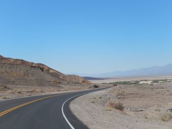 Road amidst desert against clear sky