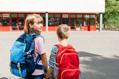 A boy and a girl, brother and sister with backpacks on their backs go to school together 