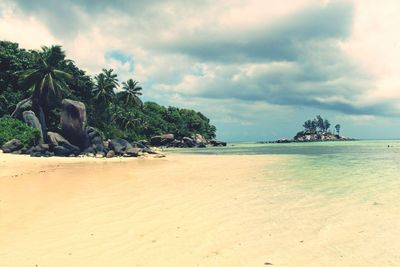 Scenic view of beach against cloudy sky