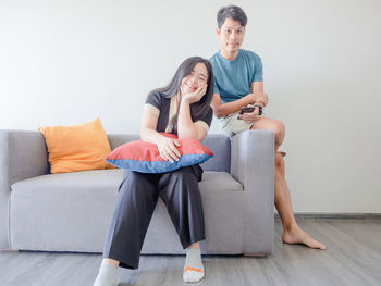 Young woman using laptop while sitting on sofa at home