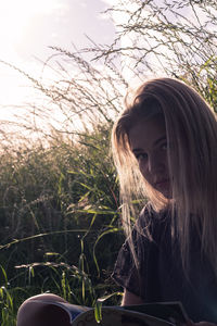 Portrait of beautiful woman with long blond hair while reading book on grassy field