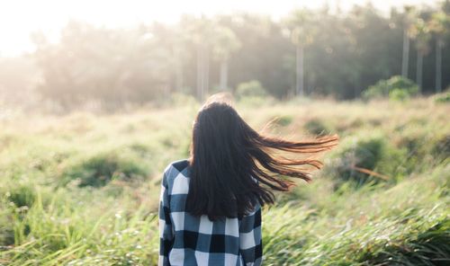 Woman standing on grassy field in forest