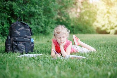 Cute girl lying down on grass at park