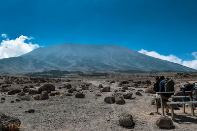 Rear view of people on mount kilimanjaro against blue sky