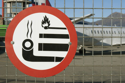 Close-up of no smoking sign mounted on fence at airport