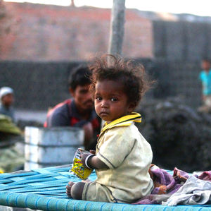 Portrait of homeless boy sitting on cot