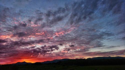 Silhouette landscape against dramatic sky during sunset