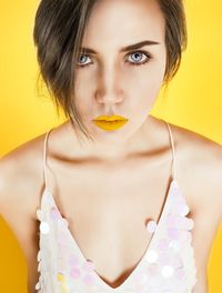 Portrait of confident young woman against yellow background