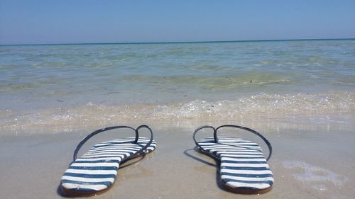 High angle view of shoes on beach against clear sky