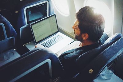 Man using laptop in airplane