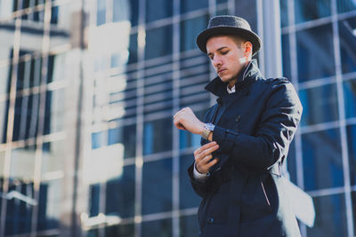 Man in coat and hat standing in city