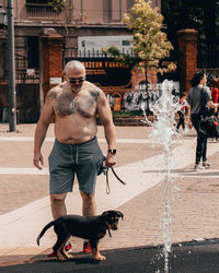 Full length of shirtless man with fountain in city