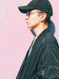 Portrait of young man looking away while standing against wall