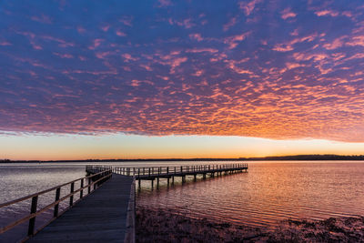 Jetty leading towards sea against sky during sunset