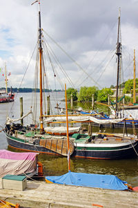 Sailboats moored at harbor against sky