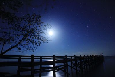 Silhouette pier over sea against sky at night