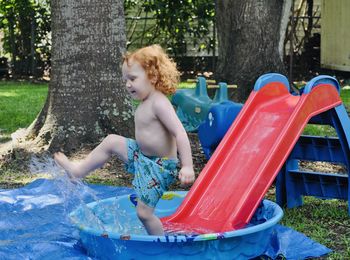 Boy kicking water out of kiddie pool