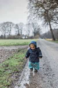 Boy playing dirt road during rainy season