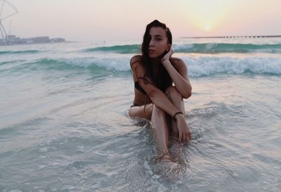 Portrait of beautiful woman at beach against sky during sunset