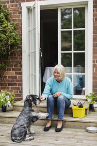 Senior woman sitting with dog at doorway