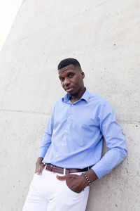 Portrait of handsome stylish african american man wearing white jeans and blue shirt, brown belt