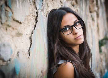 Beautiful young woman standing against old wall