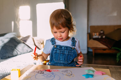 Cute girl drawing on paper at home