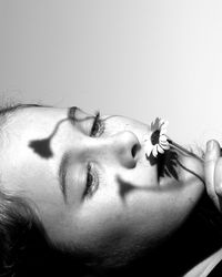 Close-up of thoughtful girl holding flower against wall