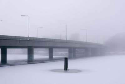 Bridge over snow covered street against sky