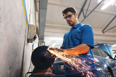 Low angle view of mechanic welding in garage