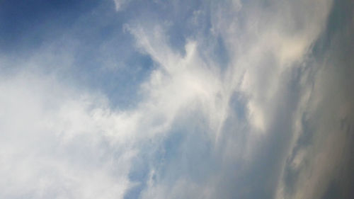 Low angle view of sunlight streaming through clouds