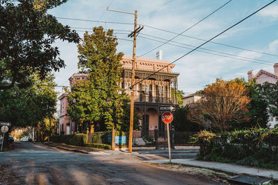 Street amidst trees and buildings against sky