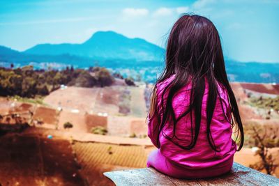 Rear view of woman looking at mountains against sky