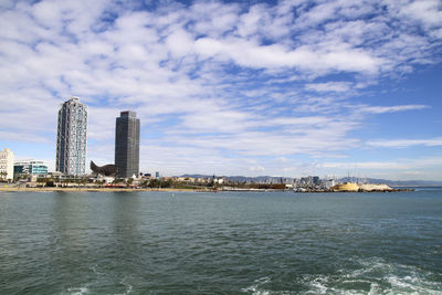 Sea by city buildings against sky