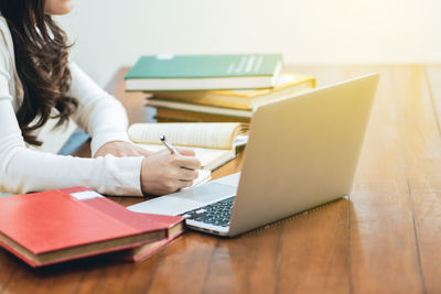 Midsection of woman using laptop on table