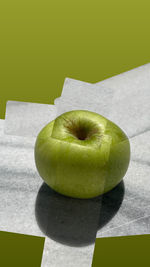 Close-up of apple on table against green background