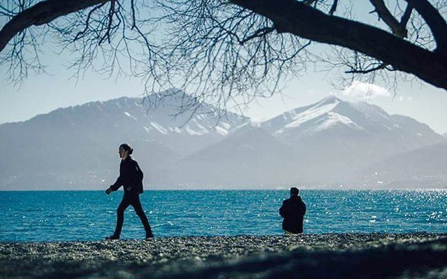 mountain, water, tranquility, rear view, tranquil scene, scenics, leisure activity, beauty in nature, lifestyles, men, full length, nature, sea, mountain range, silhouette, clear sky, sky, lake