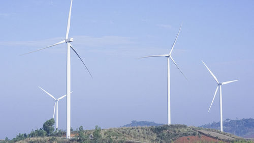 Wind turbines on landscape against sky