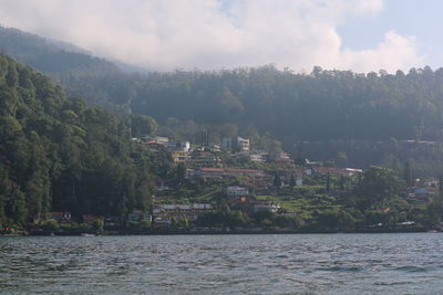 Scenic view of sea by buildings against sky