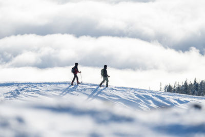 People on snowcapped mountain against sky