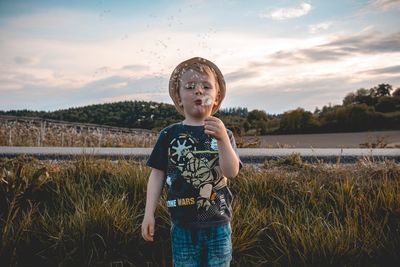 Full length of boy standing on land against sky