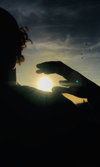 Silhouette man hand against sky during sunset