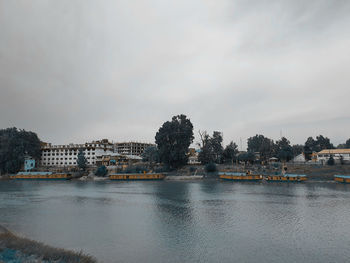 Scenic view of river by buildings against sky