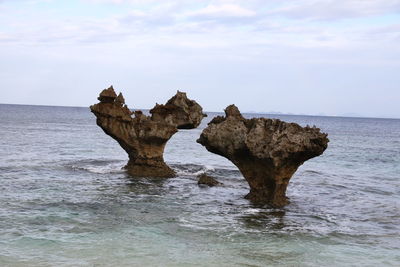 Okinawa twin rock formation in sea against sky