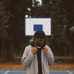 Young man holding shirt standing at basketball court