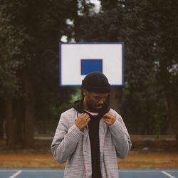 Young man holding shirt standing at basketball court