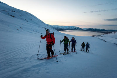 A group of skiers skiing at sunrise in iceland with water behind