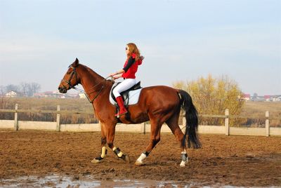 Side view of woman riding horse at ranch