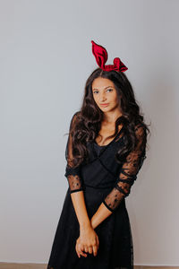 Portrait of beautiful young woman standing against wall