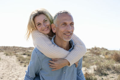 Smiling woman embracing man on sand dunes